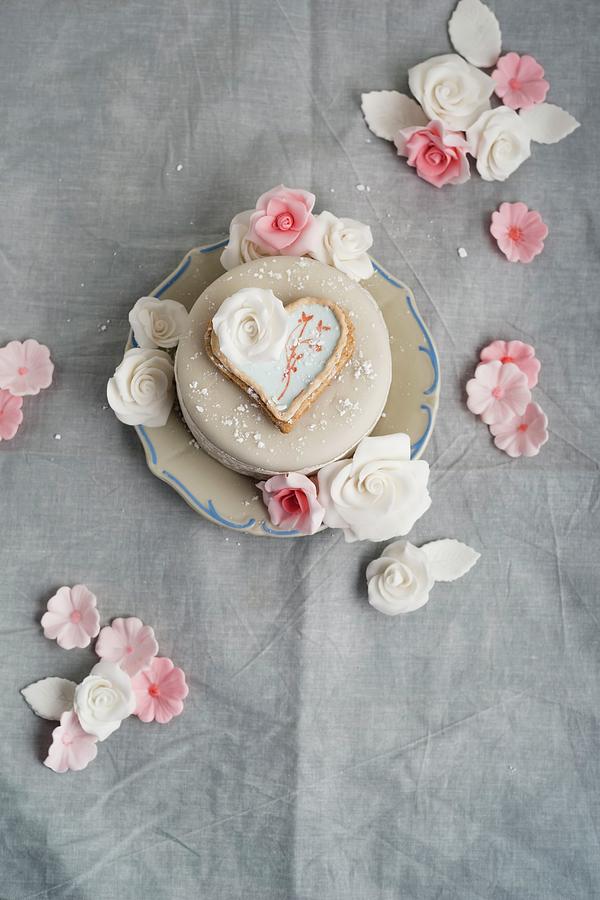 A Cake Decorated With Fondant Icing Sugar, Heart-shaped Biscuit And Sugar Roses Photograph by Mandy Reschke