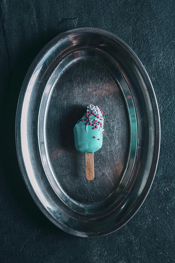 A Cake Pop In The Shape Of An Ice Lolly With Brightly Coloured Icing On A Silver Tray Photograph by Ltummy
