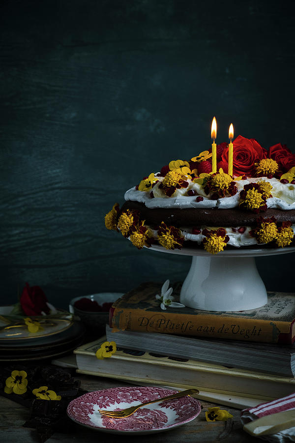 A Cake With Merengue And Chocolate Cake With Eatable Flowers With Candles Standing On Books Photograph by Lucie Beck