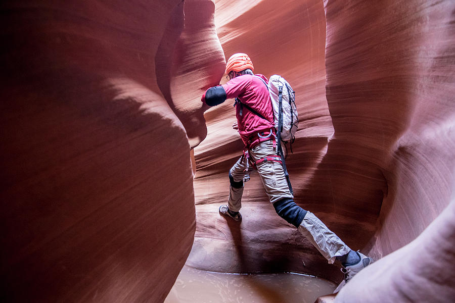 Desert Photograph - A Canyoneer Take A Big Step To Avoid Deep Pothole In Slot Canyon by Cavan Images