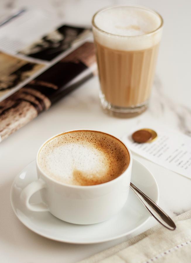 A Cappucino And A Caffe Latte Next To A Magazine Photograph by Joana Leito