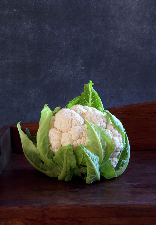 A Cauliflower On A Wooden Background Photograph by Louise Hammond
