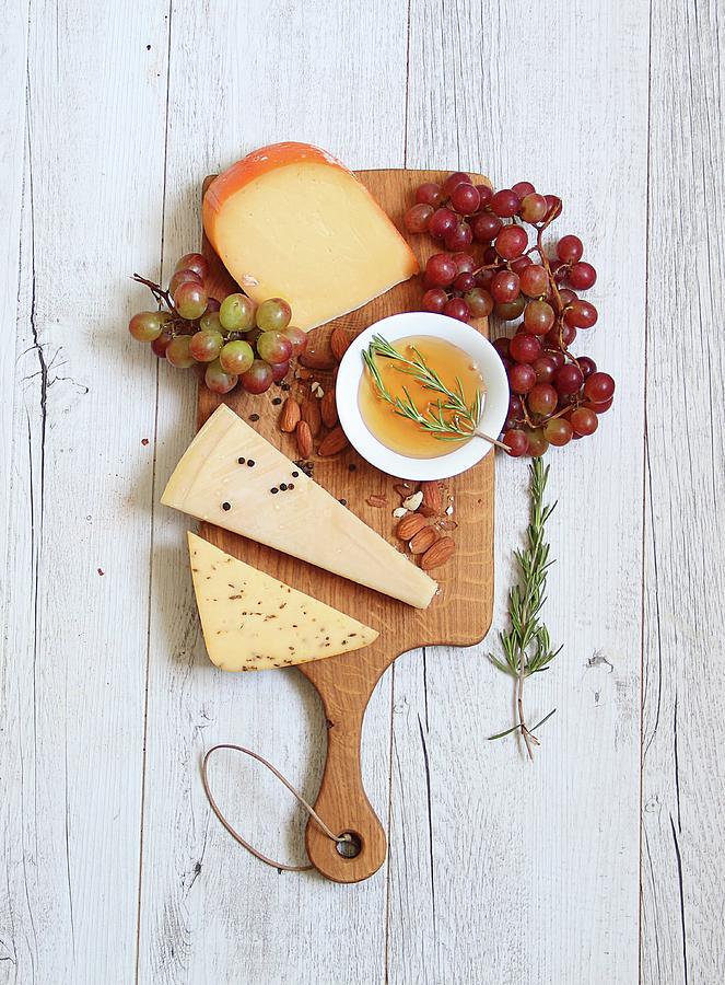 A Cheeseboard With Grapes, Almond Olive Oil And Rosemary Photograph by Milly Kay