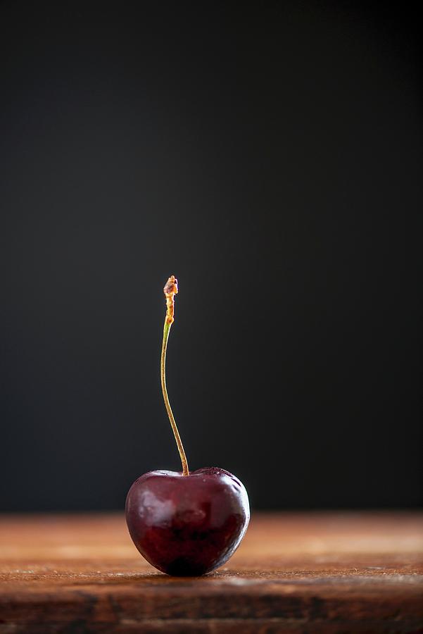 A Cherry On A Wooden Table Photograph by Kapoor, Nitin