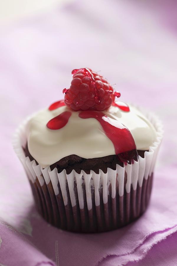 A Chocolate And Raspberry Cupcake Topped With Cream, Raspberry Syrup And A Fresh Raspberry Photograph by Laurange