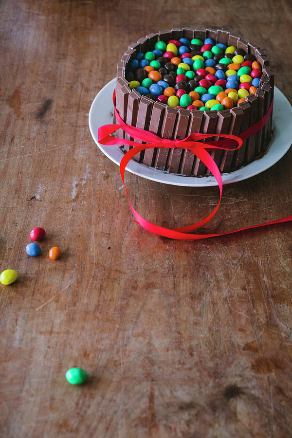 A Chocolate Cake With Chocolate Bars On A Wooden Table With A Red Ribbon For Mothers Day Photograph by Lucie Beck