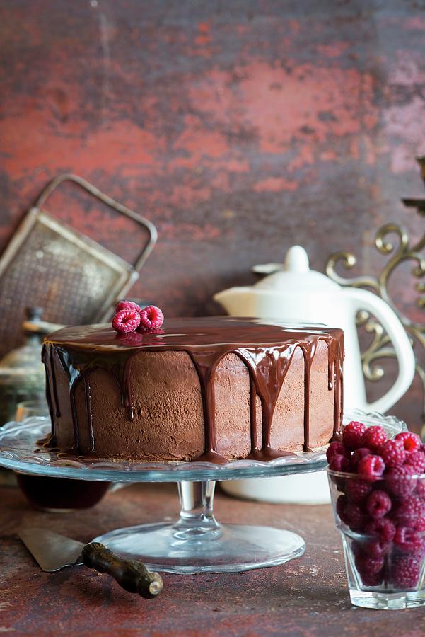 A Chocolate Cake With Chocolate Glaze And Raspberries On A Cake Stand Photograph by Irina Meliukh