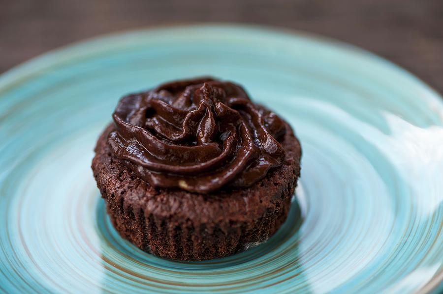 A Chocolate Cupcake With Chocolate Frosting On A Blue Plate Photograph by Gabriela Lupu