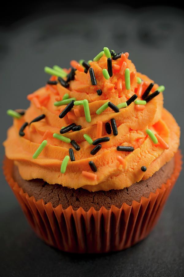 Halloween Photograph - A Chocolate Cupcake With Orange Buttercream And Sugar Sprinkles For Halloween by Ewa Rejmer