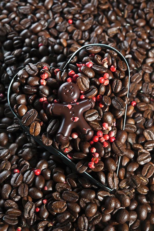 A Chocolate Figure On Top Of Coffee Beans With Red Peppercorns In A Heart-shaped Cutter Photograph by Atelier Hmmerle