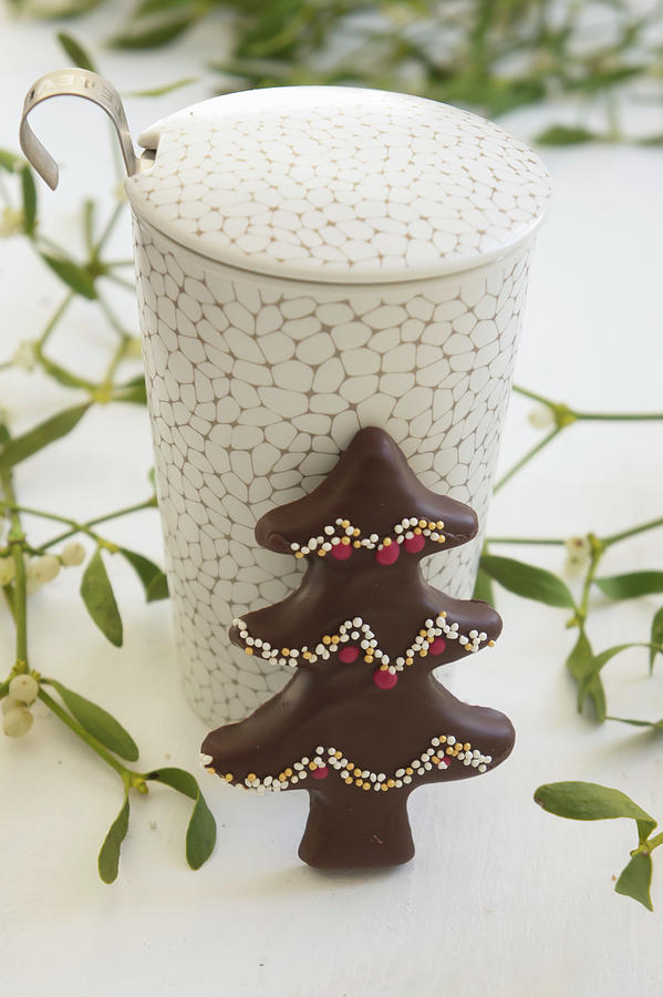 A Chocolate-glazed Gingerbread Christmas Tree With Sprinkles Against A Mug Of Tea Photograph by Martina Schindler