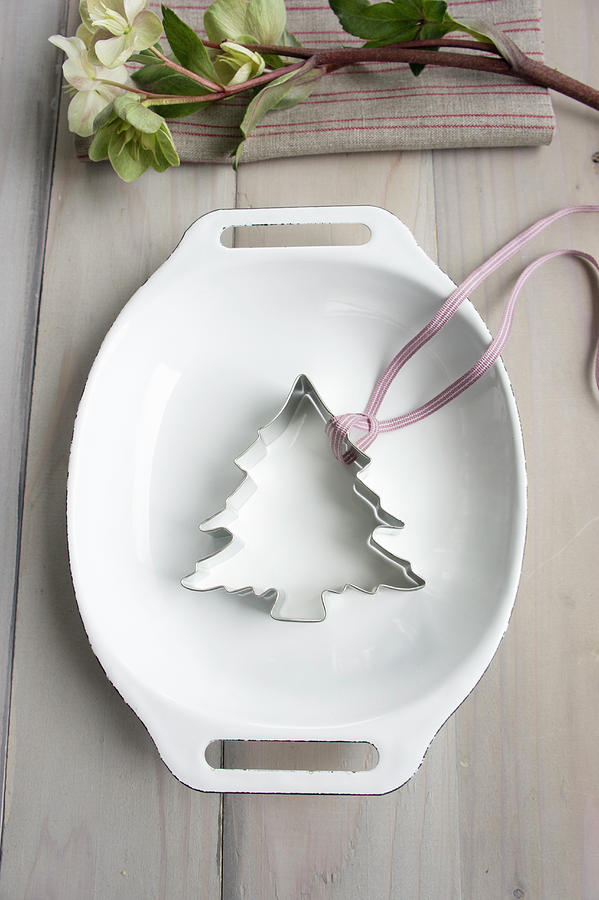 A Christmas Tree Cutter And A Ribbon In An Enamel Baking Dish Photograph by Martina Schindler