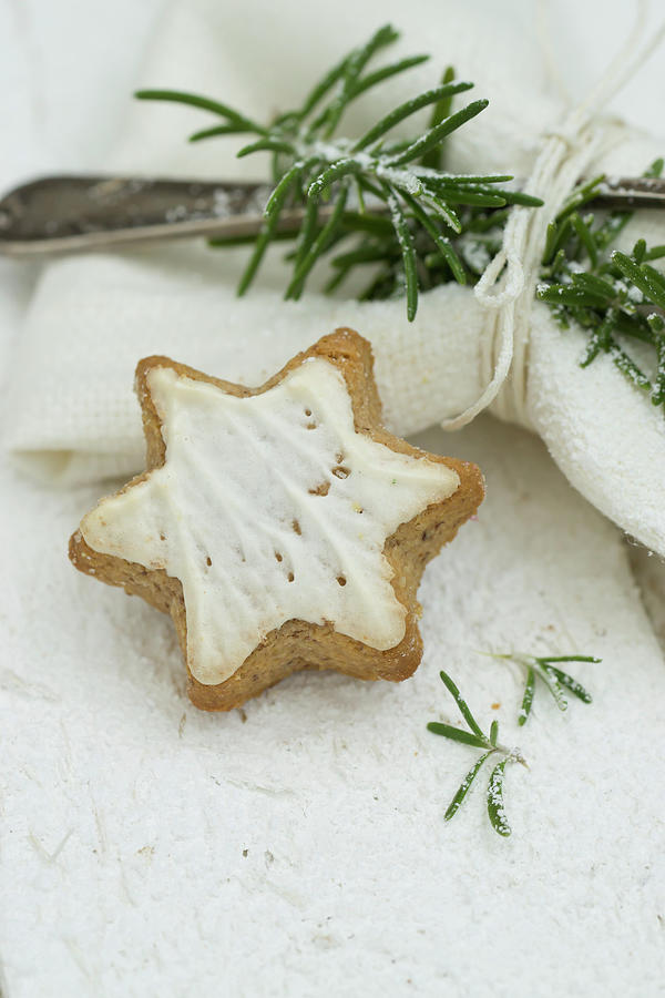 A Cinnamon Star Next To A Napkin With A Silver Fork And A Sprig Of Rosemary Photograph by Martina Schindler