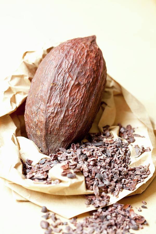 A Cocoa Fruit And Pieces Of Broken Cocoa Beans On A Piece Of Paper Photograph by Hilde Mche
