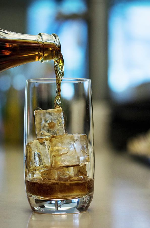 A Cola Drink Being Poured Into A Glass With Ice Cubes Photograph by Vivi Dangelo