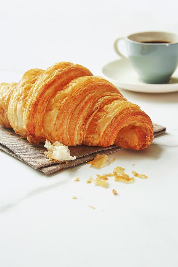 A Croissant With An Espresso Cup In The Background Photograph by Tracey Kusiewicz