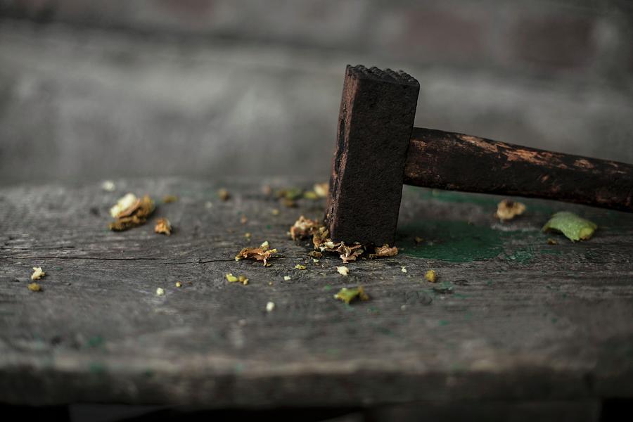 A Crushed Walnut With A Hammer On A Wooden Table Photograph by Nika Moskalenko