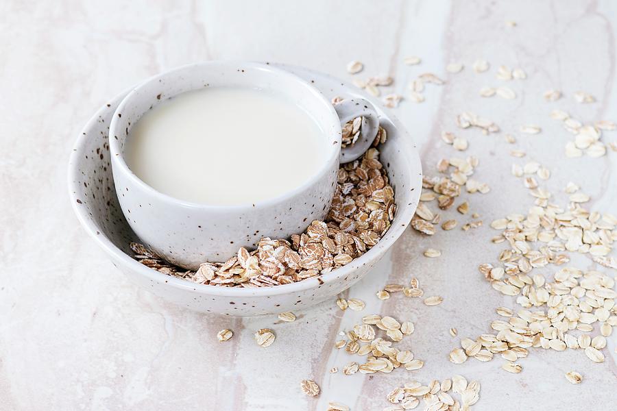 A Cup Of Oat Milk In Bowl Of Oats On A Marble Surface Photograph by Natasha Breen