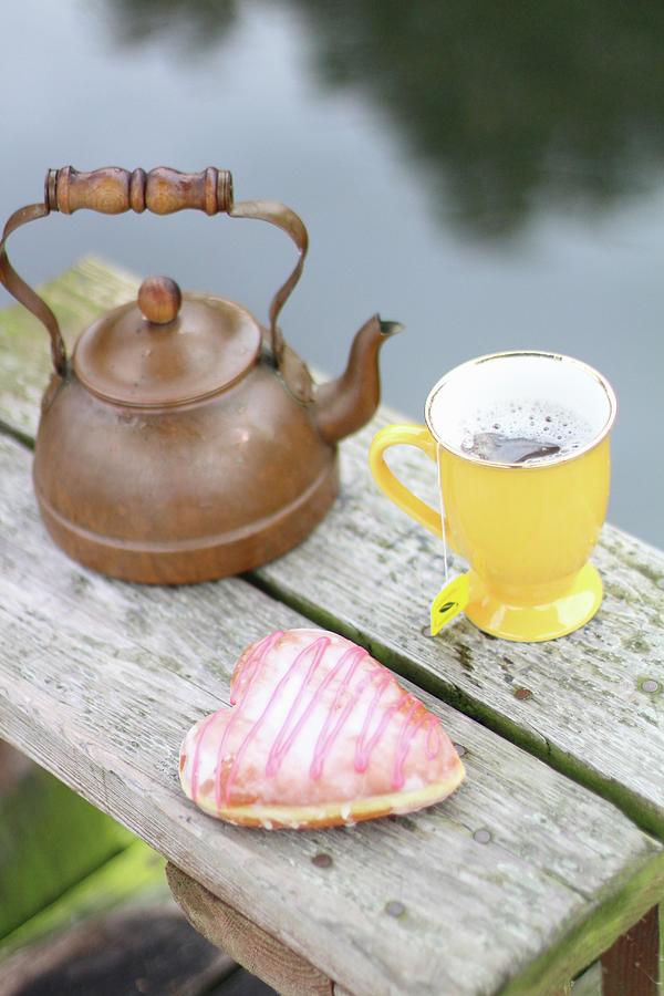 A Cup Of Tea And A Heart-shaped Doughnut On The Bank Of A Lake Photograph by Sylvia E.k Photography