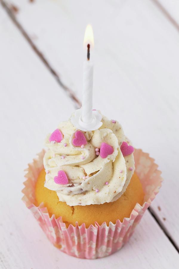 A Cupcake Decorated With Buttercream, Pink Hearts And A Birthday Candle Photograph by Lydie Besancon