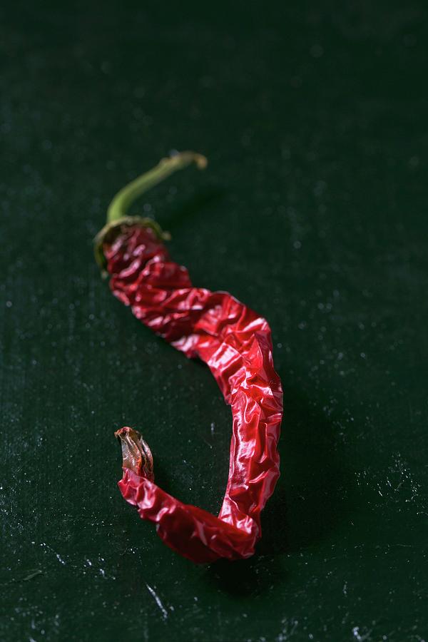 A Dried Red Chilli Pepper On A Dark Surface Photograph by Natasha Breen