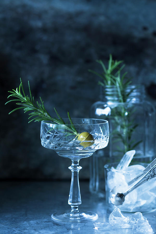 A Drink Garnished With An Olive And A Sprig Of Rosemary Photograph by Katrin Winner