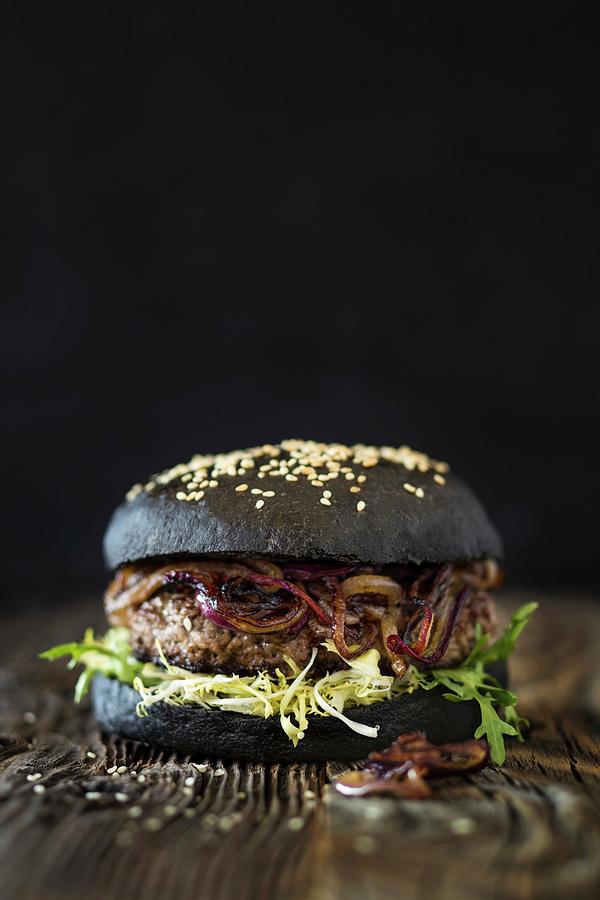 A Dry Aged Hamburger With Fried Red Onions And A Black Bun Photograph by Jan Wischnewski