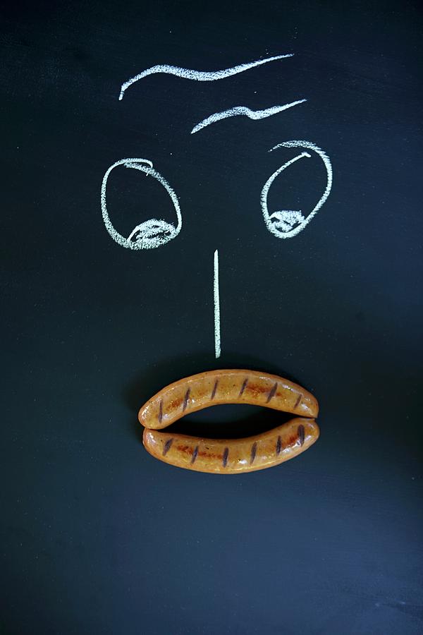 A Face Drawn With Chalk With Two Sausages As A Mouth Photograph by Jo Kirchherr