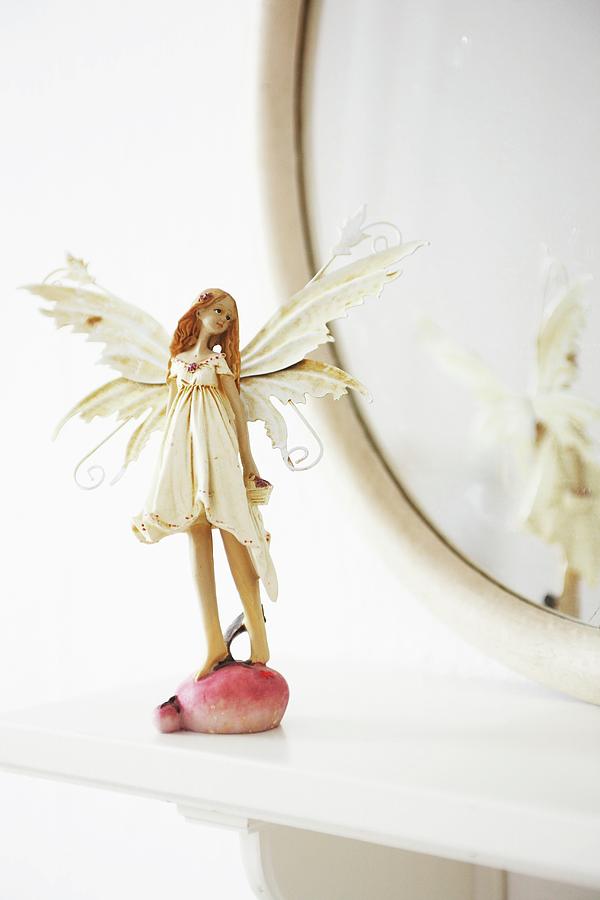 A Fairy Figurine In Front Of An Oval Mirror On A Shelf Photograph by Heidi Frhlich
