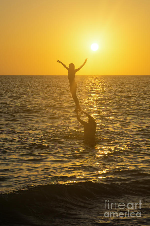A father lifts his daughter out of the water along the beach at  Photograph by William Kuta
