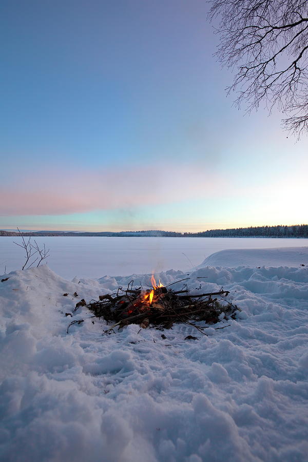 A fire is burning at the shore of a frozen lake Photograph by ...