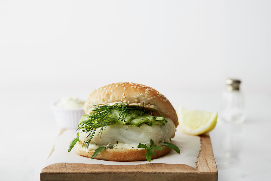 A Fish Burger With Cucumber And Dill On A Wooden Chopping Board Photograph by Kathrin Mccrea