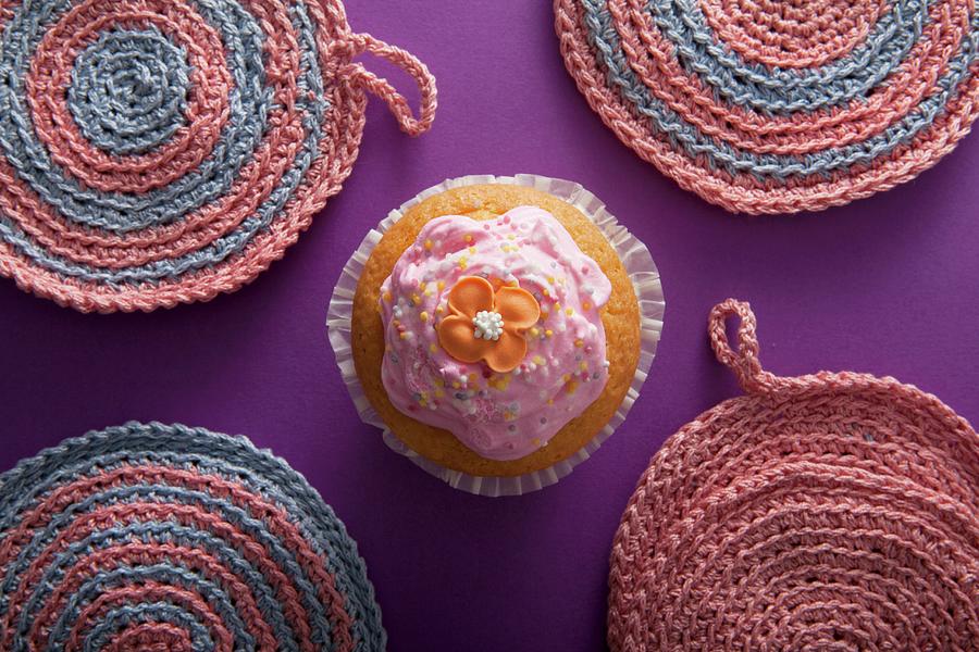 A Flower Cupcake Between Crocheted Pot Holders Photograph by Blueberrystudio