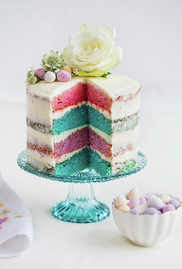 A Four-layer Rainbow Cake With White Frosting, Easter Eggs And Flowers sliced Photograph by Lucy Parissi