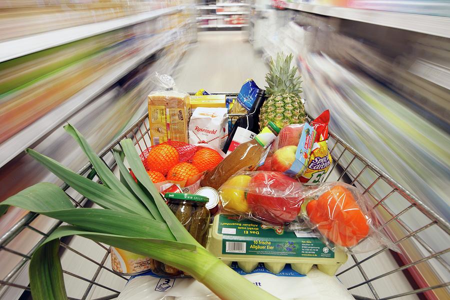 A Full Shopping Trolley Being Pushed Through A Supermarket Photograph by Gerhard Bumann