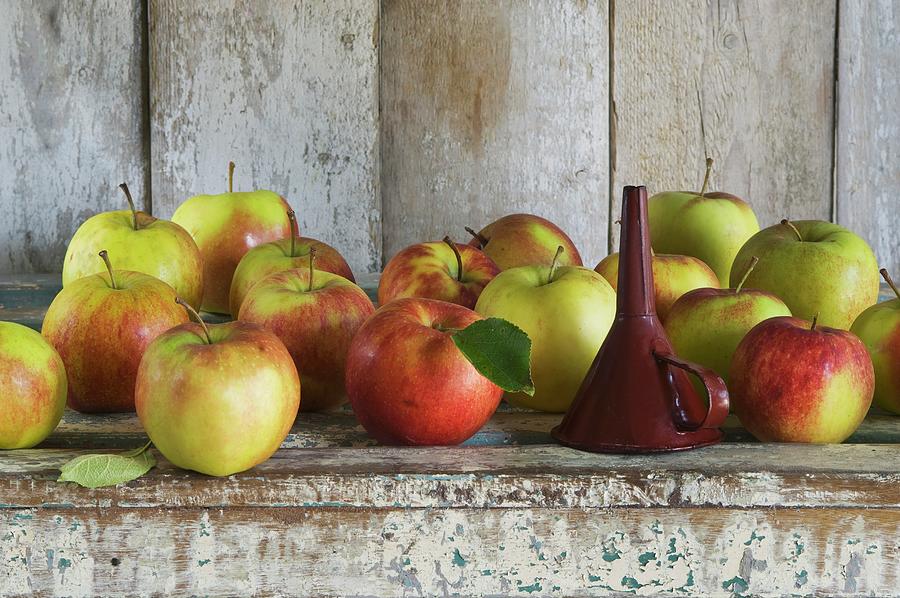 A Funnel And Jonagold Apples On A Rustic Shelf Photograph by Achim Sass