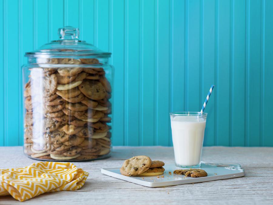A Giant Cookie Jar Filled With Chocolate Chip Cookies With A Plate Of Cookies And Milk In The Foreground Photograph by Don Crossland