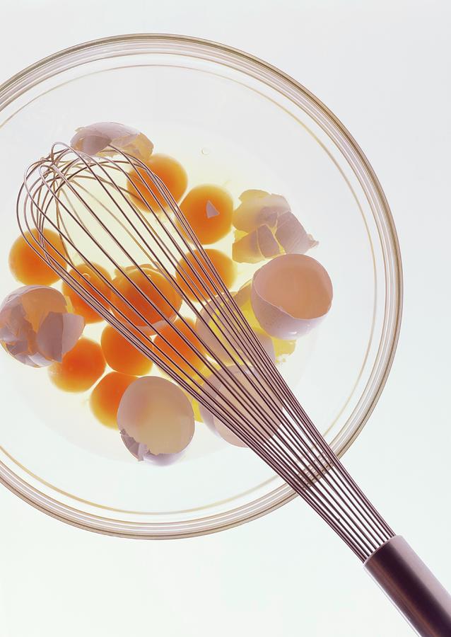 A Glass Bowl With Raw Eggs, Eggshells And A Balloon Whisk Photograph by Michael Wissing