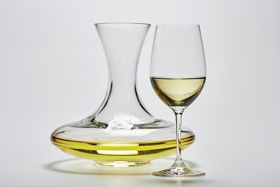 A Glass Carafe And A Glass Of White Wine On A White Surface Photograph by Herbert Lehmann
