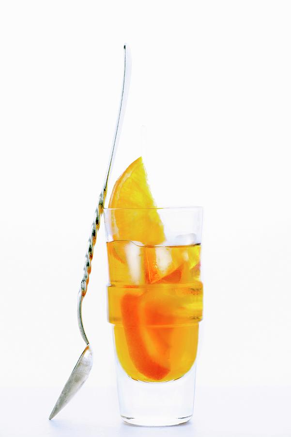 A Glass Of Amaro Nonino, An Italian Herbal Liqueur, With Ice Cubes And Orange Slices Photograph by Jamie Watson