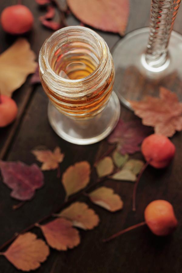 A Glass Of Dessert Wine With Autumn Leaves And Berries On A Wooden Table Photograph by Katharine Pollak
