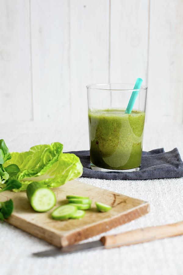 A Glass Of Ginger And Cucumber Smoothie With A Straw Photograph by Claudia Timmann