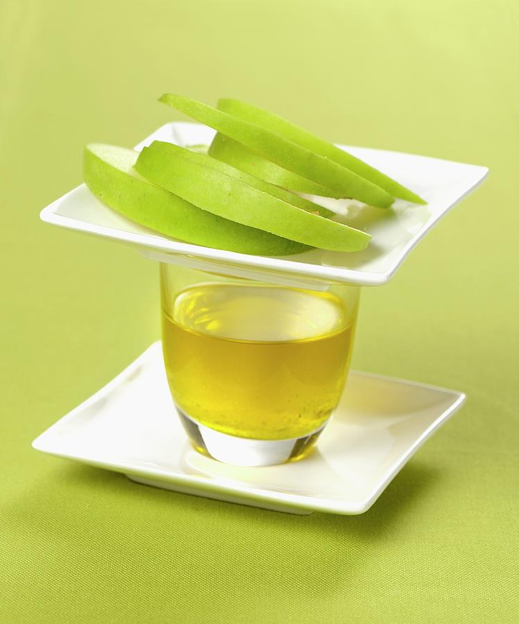 A Glass Of Olive Oil And Sliced Green Apple Photograph by Franco Pizzochero
