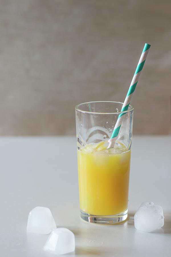 A Glass Of Orange Juice With Ice Cubes And A Retro Straw Photograph by Natasha Breen