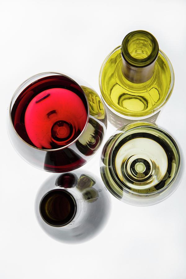 A Glass Of Red Wine, A Glass Of White Wine And Wine Bottles Photograph by Uwe Merkel