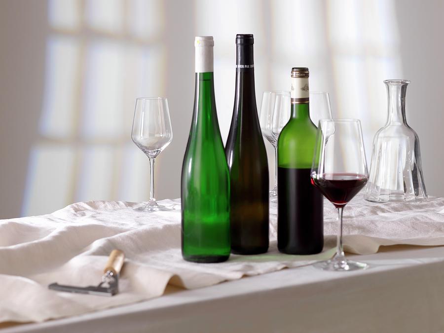 A Glass Of Red Wine, Bottles Of Wine And Empty Glasses Photograph by Ulrike Koeb