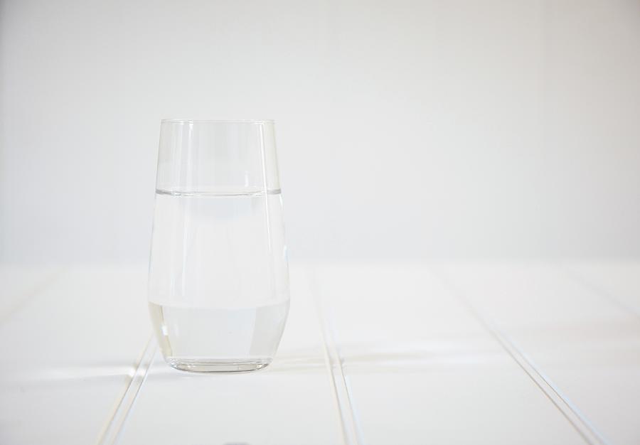 A Glass Of Water On A White Wooden Table Photograph by Simon Scarboro