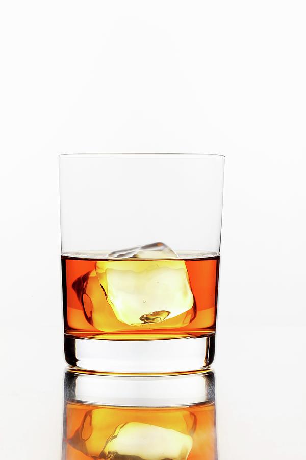 A Glass Of Whiskey With An Ice Cube Photograph by Perry Jackson