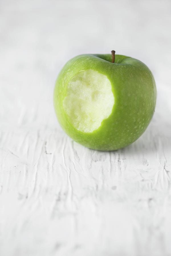 A Granny Smith Apple With A Bite Taken Out Photograph by Malgorzata Laniak