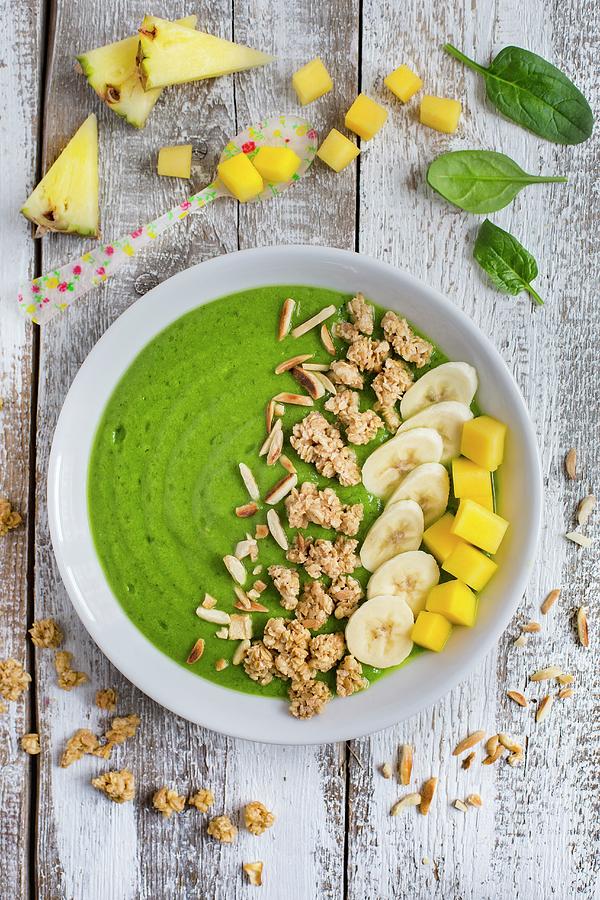 A Green Smoothie Bowl With Spinach, Mango, Pineapple, Banana And Muesli Photograph by Tina Engel
